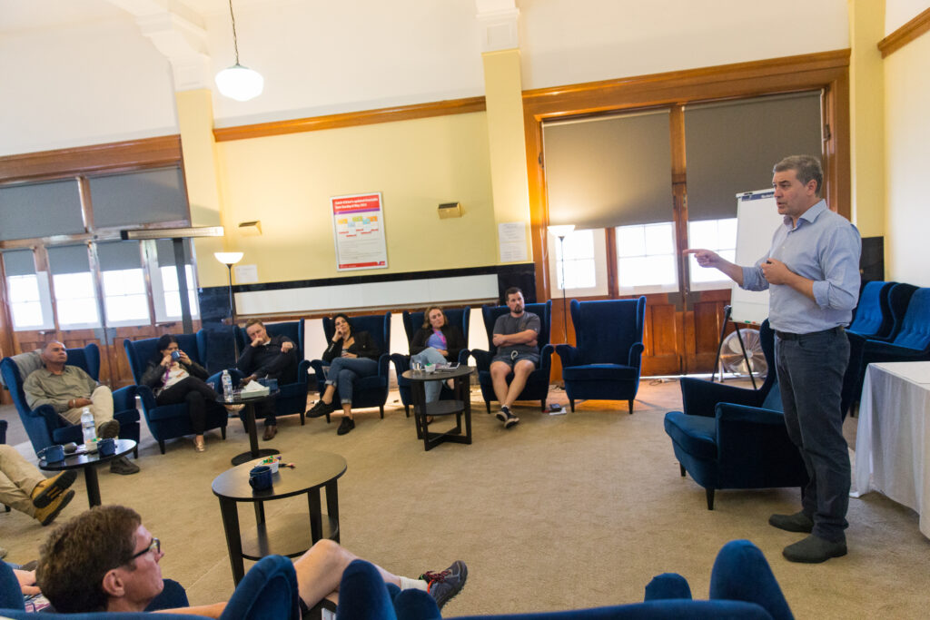 Room full of people sitting in high backed arm chairs in semi-circle